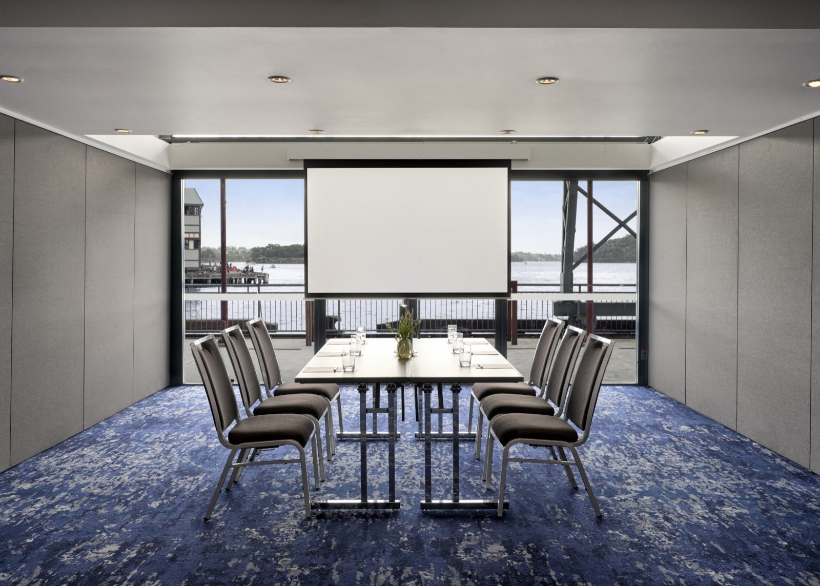 A boardroom in the Dawes Point Rooms with a projector screen and Walsh Bay through the windows
