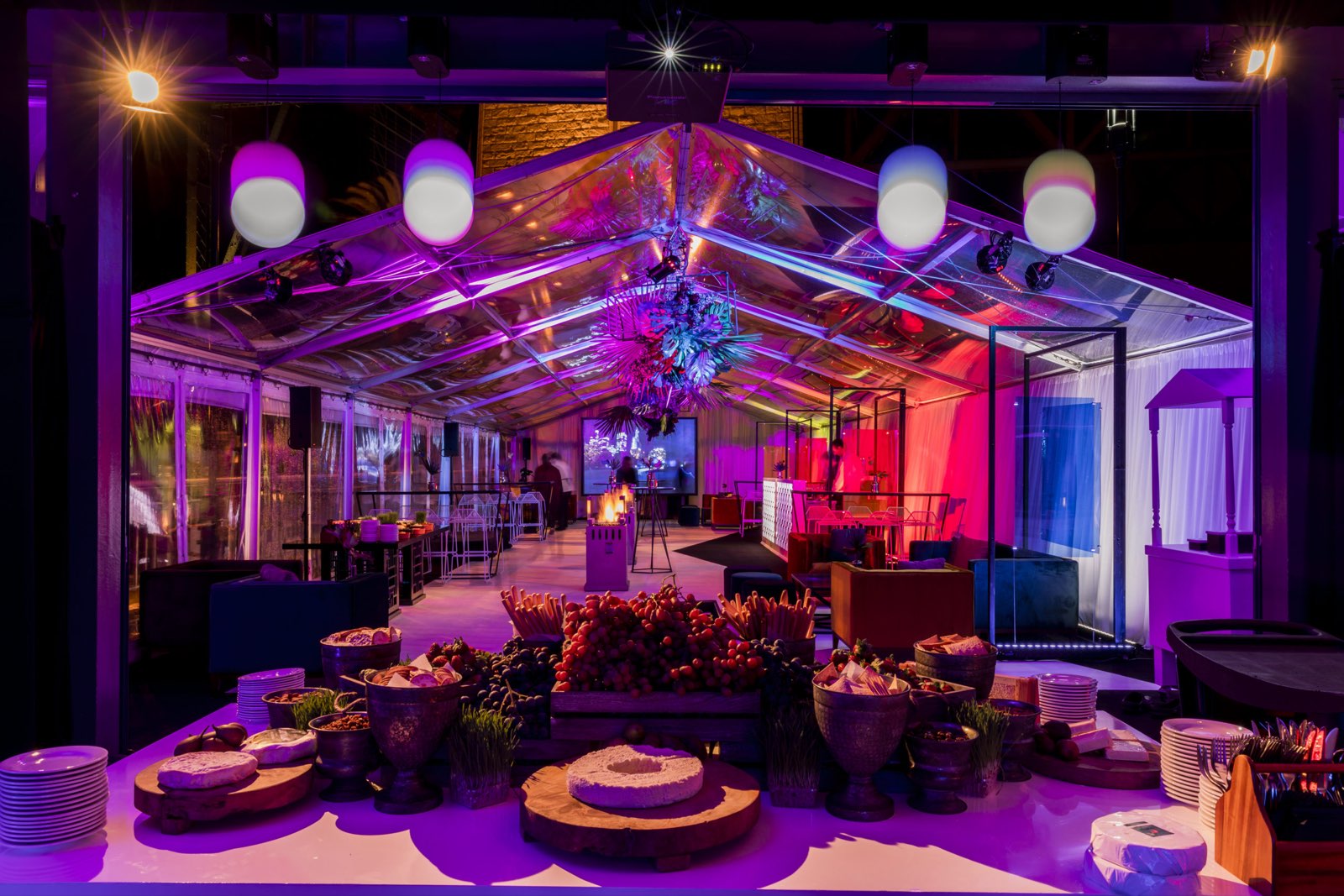 A festive party in the marquee with coloured lighting and grazing table
